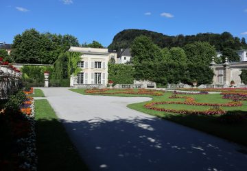 a large white building with a garden and a driveway