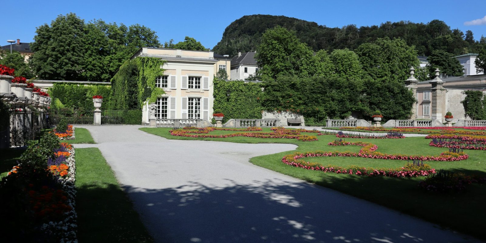 a large white building with a garden and a driveway