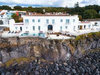 a white building with a pool on a cliff