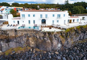 a white building with a pool on a cliff
