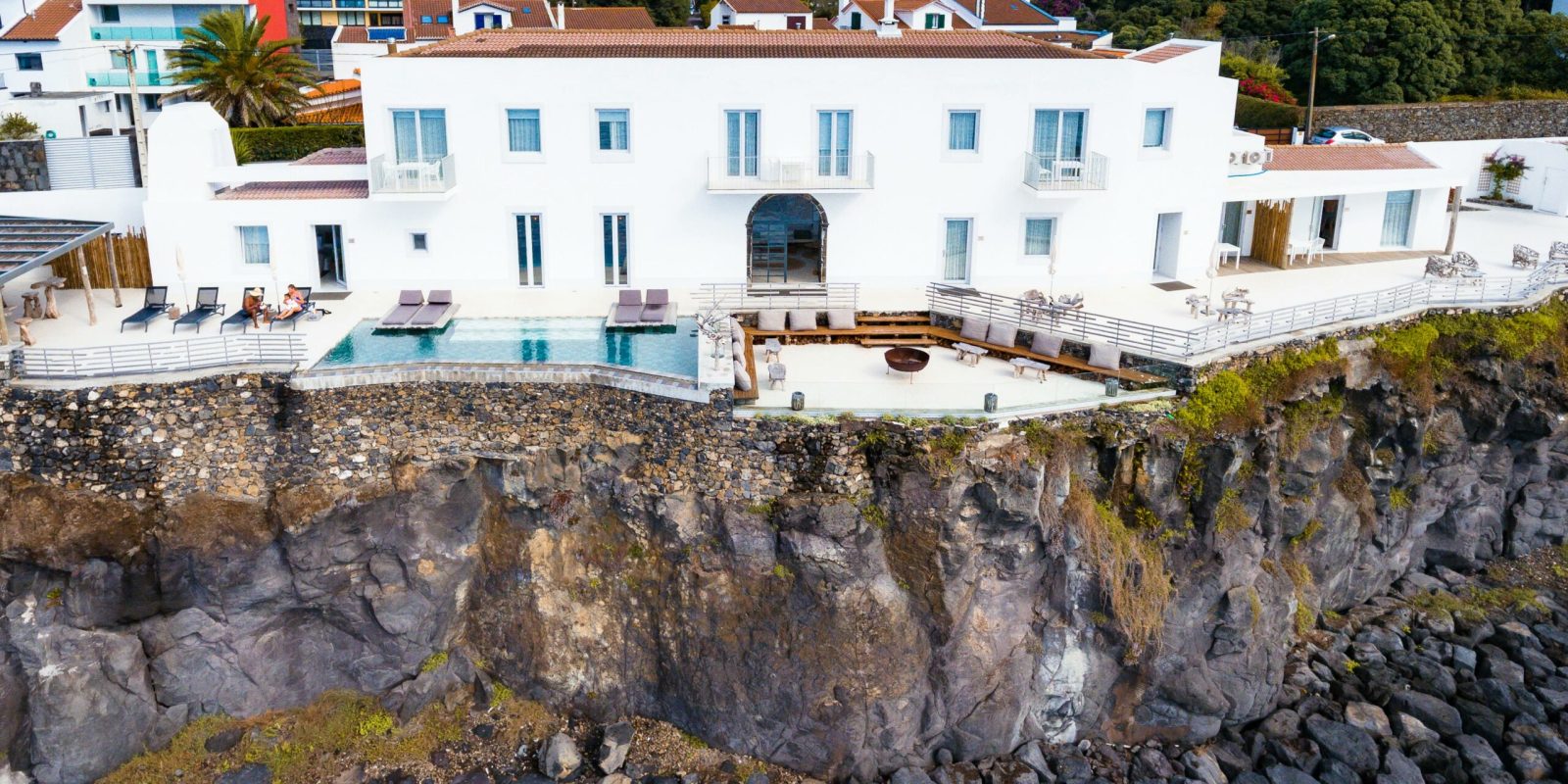 a white building with a pool on a cliff