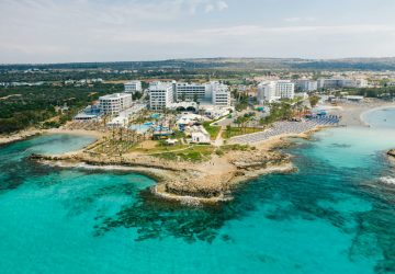 a beach with a group of buildings and a body of water