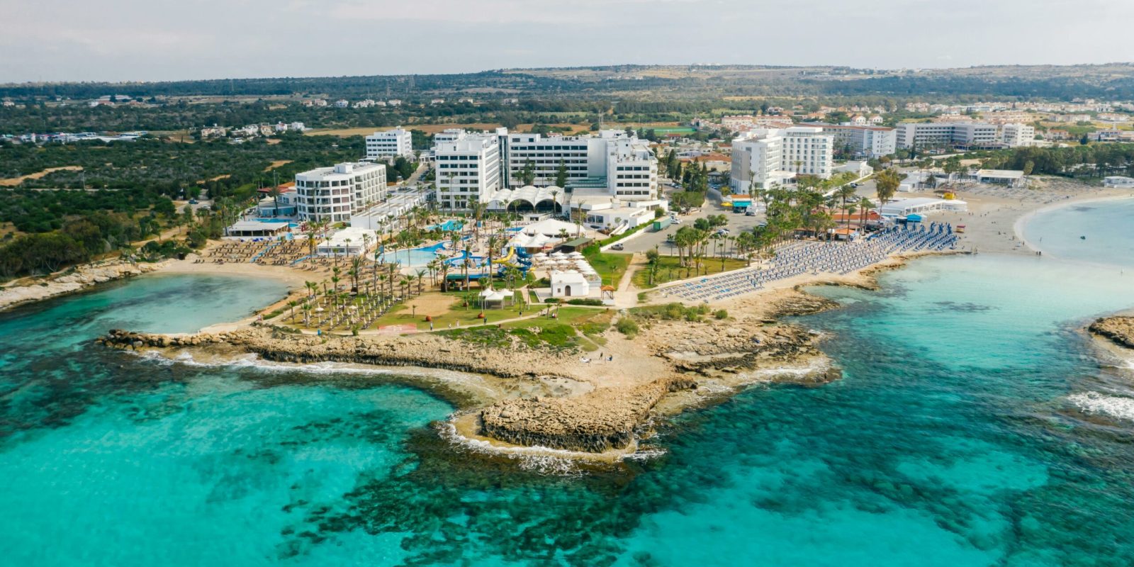 a beach with a group of buildings and a body of water