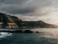 a body of water with a rocky cliff and a beach