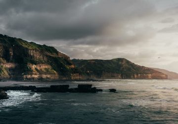 a body of water with a rocky cliff and a beach