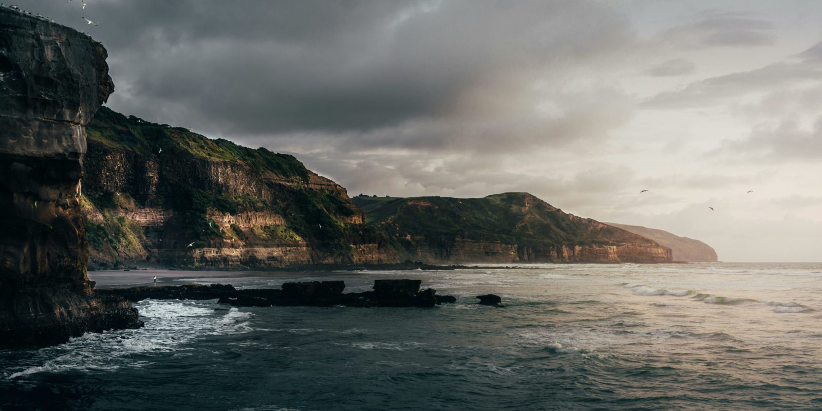 a body of water with a rocky cliff and a beach