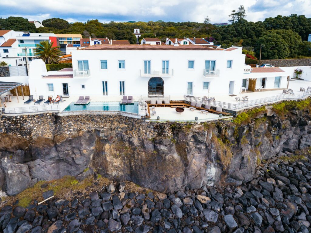 a white building with a pool on a cliff